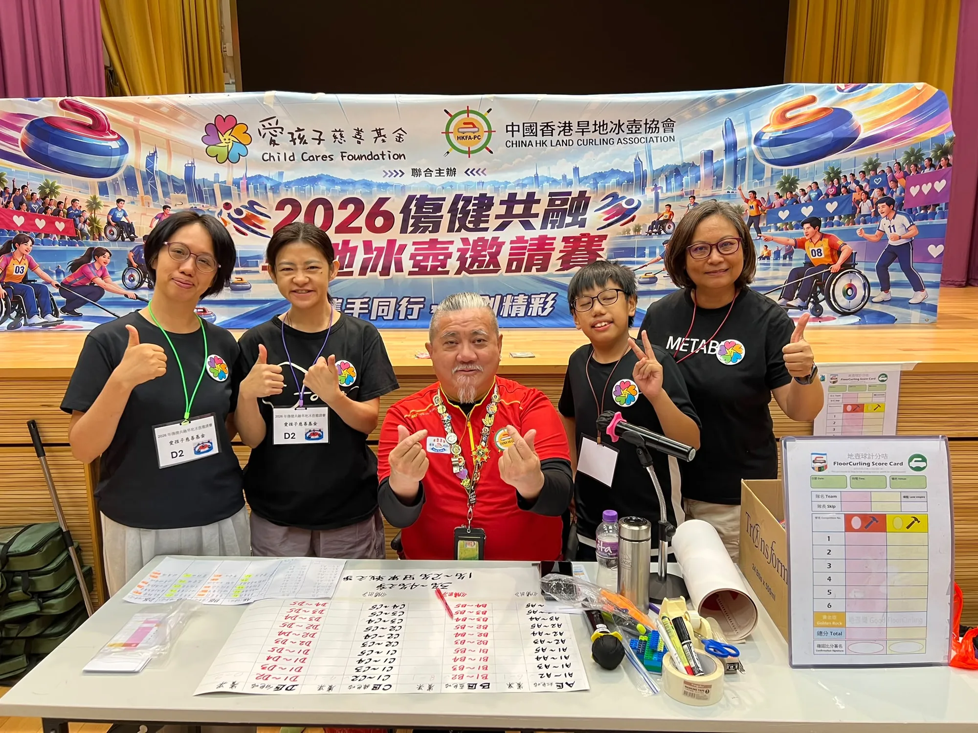 四位工作人員在活動橫額前手持活動物資合照