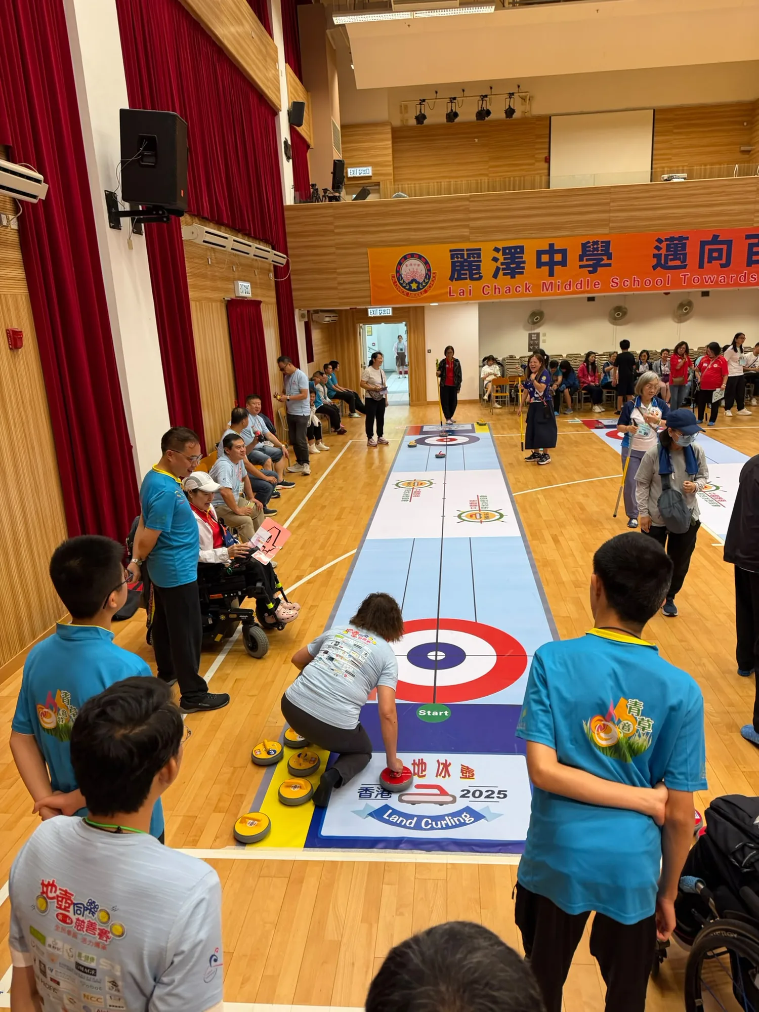 場邊參加者觀看旱地冰壺沿賽道滑行